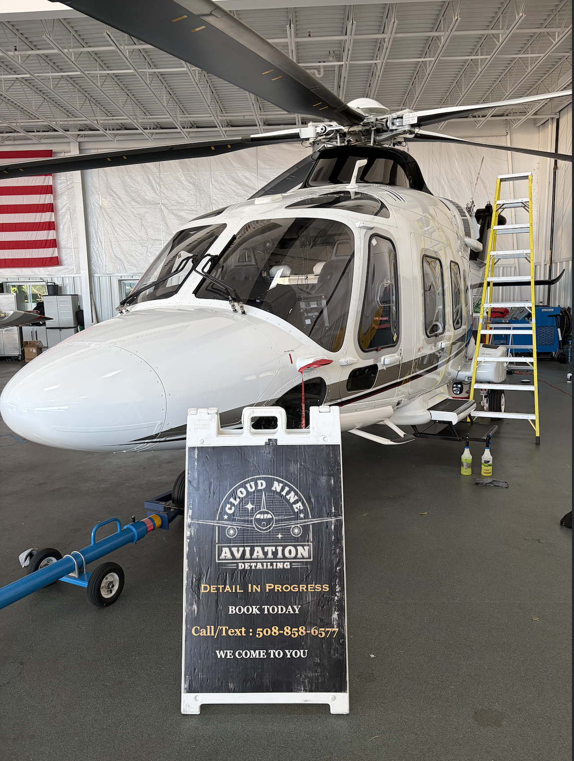 White helicopter inside a hangar receiving aircraft care service
