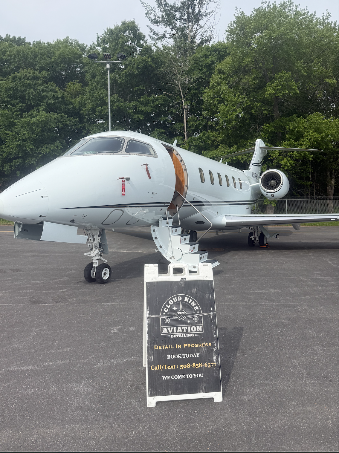 White private jet on the ramp with a Cloud Nine Aviation detailing sign